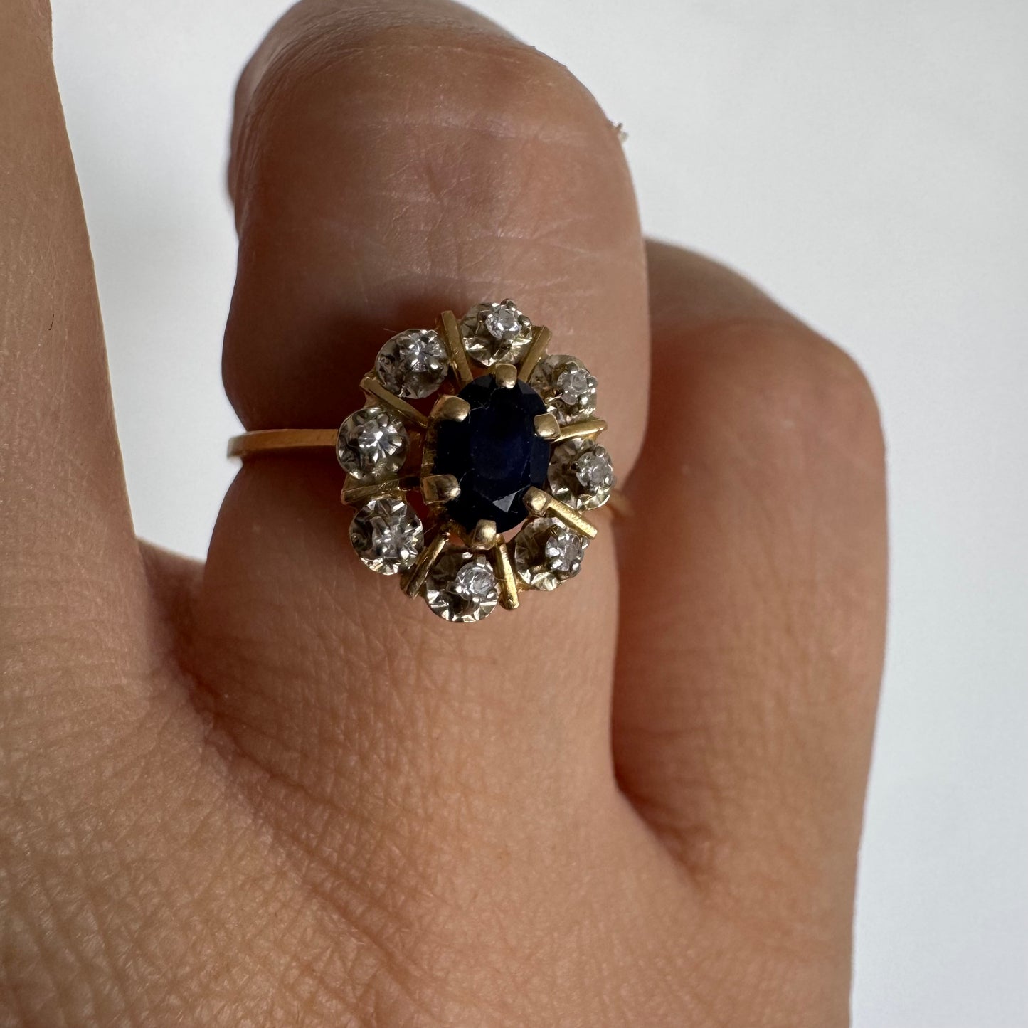 18K gold ring set with a natural blue Sapphire at its center, surrounded by a halo of sparkling Diamonds