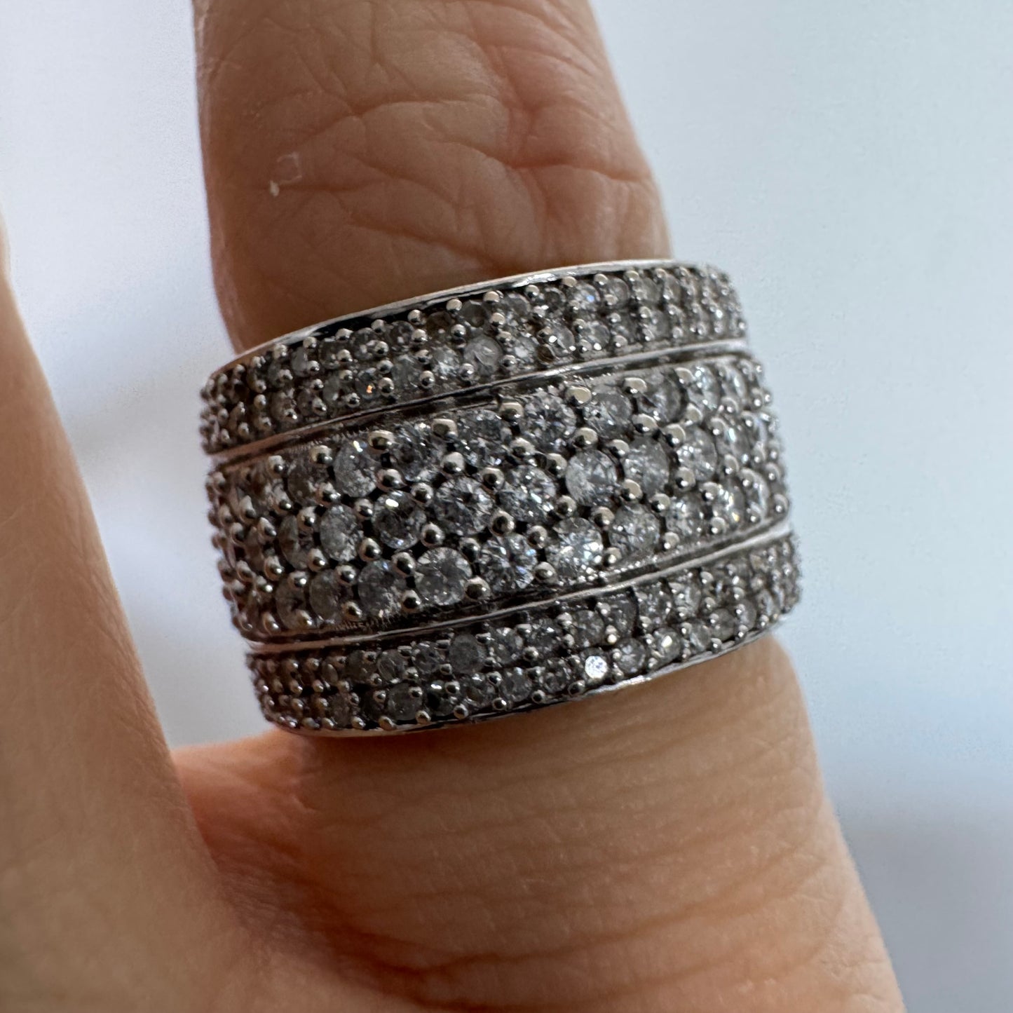 טבעת זהב לבן 18 קראט בעיצוב רחב ומרשים, משובצת יהלומים בשיבוץ פאווה צפוף המעניק ברק עשיר ונוכחות יוקרתית מכל זווית.