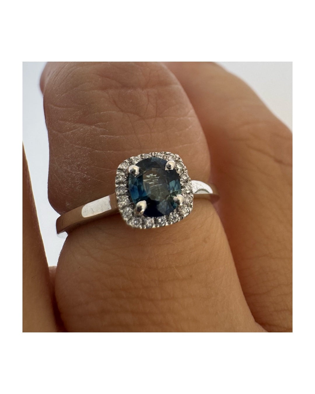 14K gold ring set with an oval blue Sapphire at the center framed by a delicate halo of sparkling Diamonds.