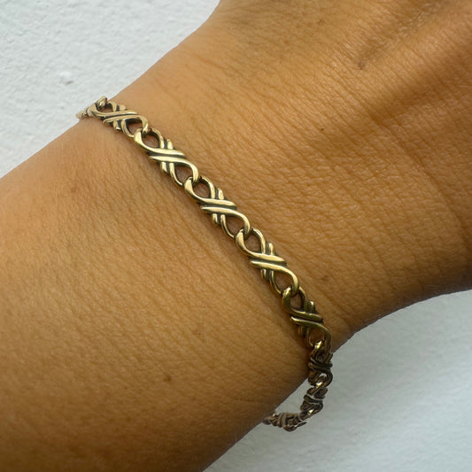 14K gold bracelet with an interwoven twisted link design and a lobster clasp closure.