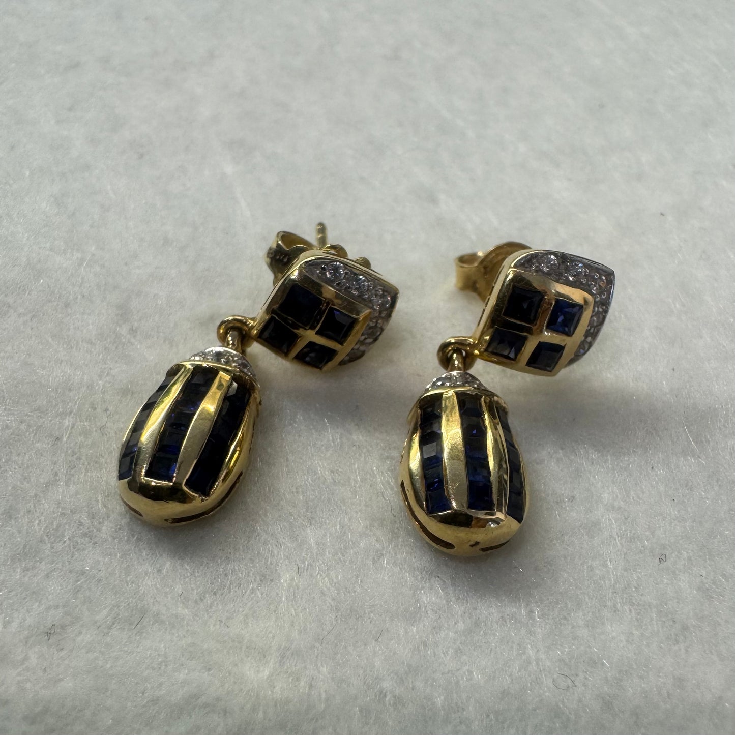 18K old drop earring set with deep blue Sapphires in a geometric pattern, accented with sparkling Diamonds.
