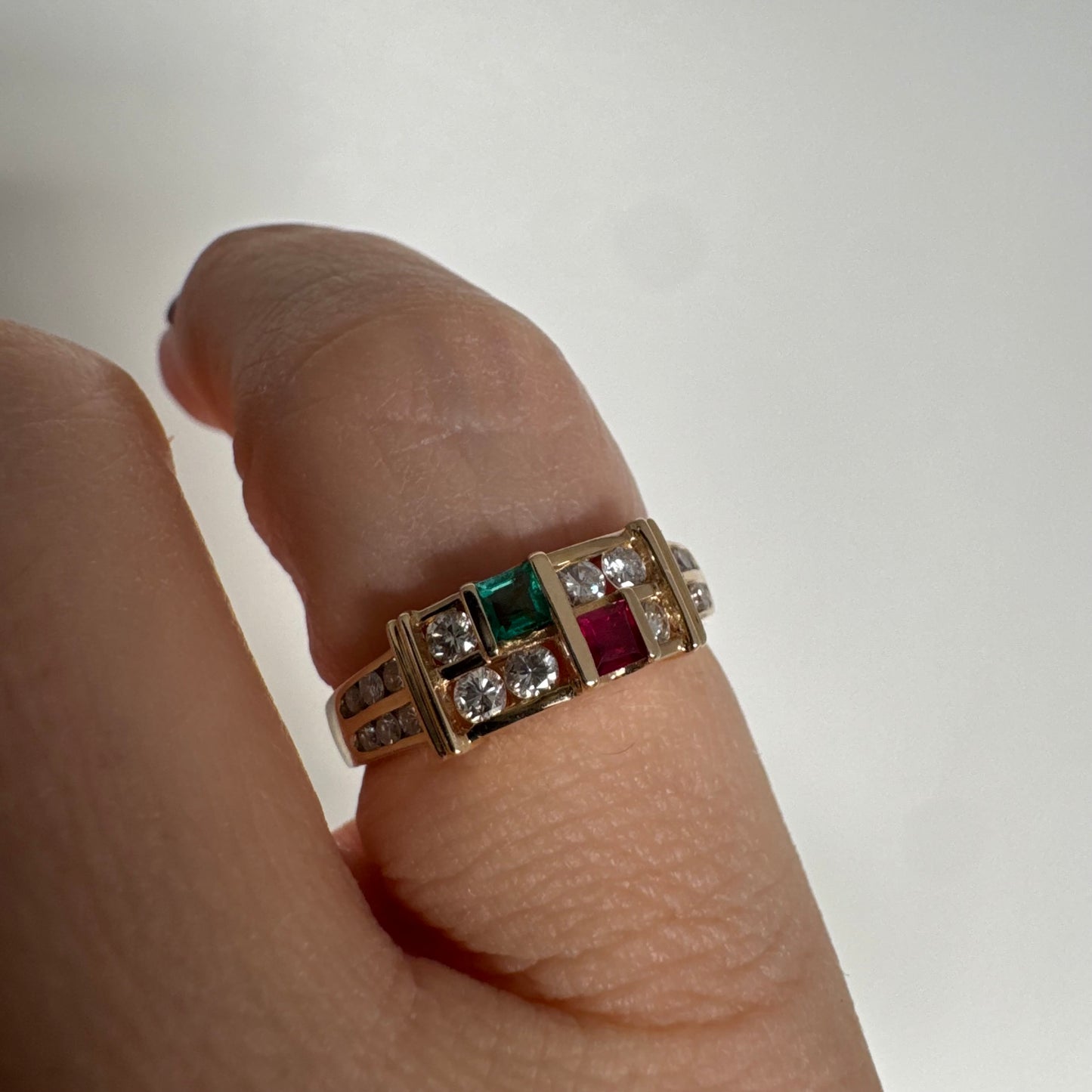 טבעת זהב צהוב 18 קראט בעיצוב גאומטרי מדורג, משובצת יהלומים עגולים לצד אבני אמרלד ורובי בחיתוך מלבני.