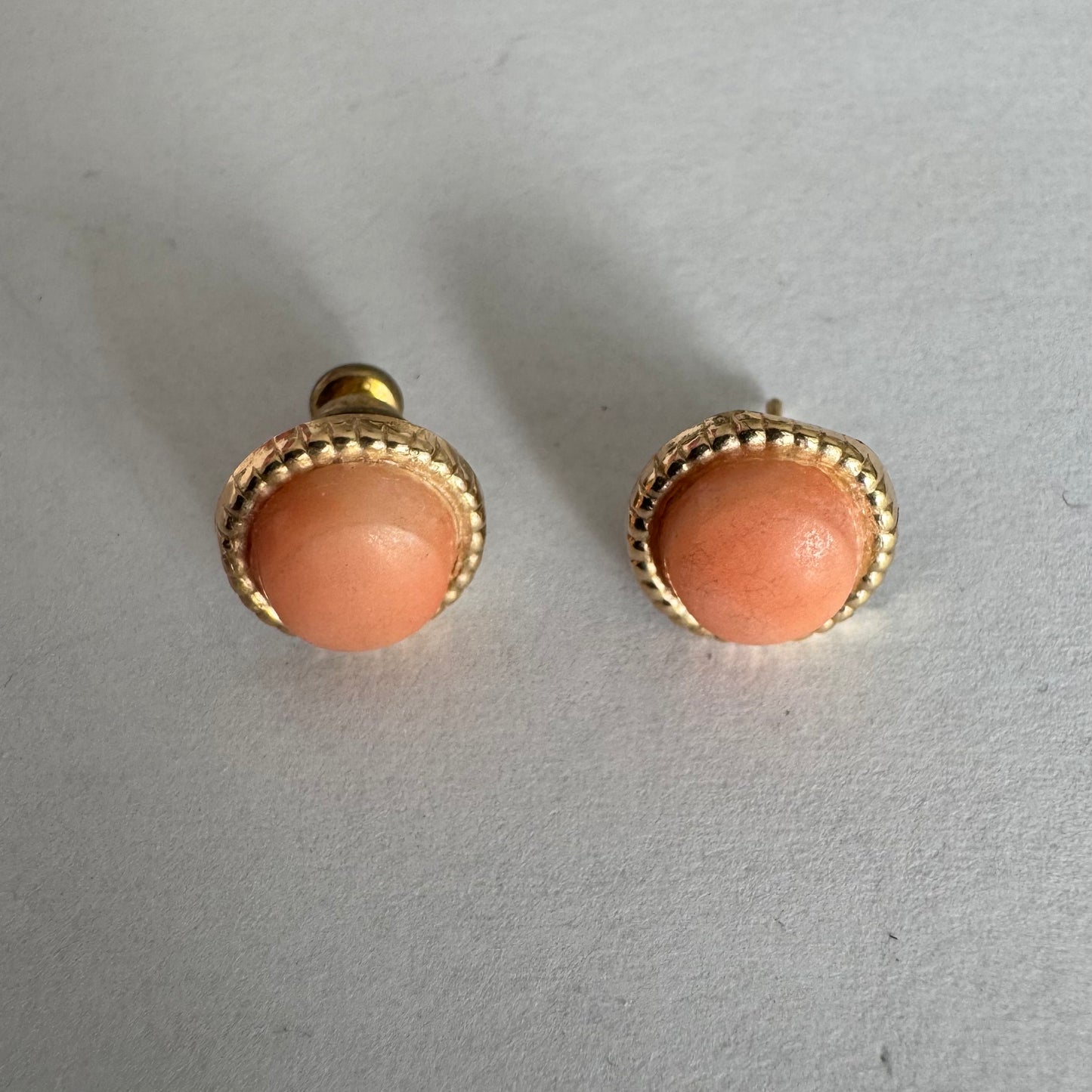 14K gold stud earrings set with natural Coral stones in a soft peach-pink tone.