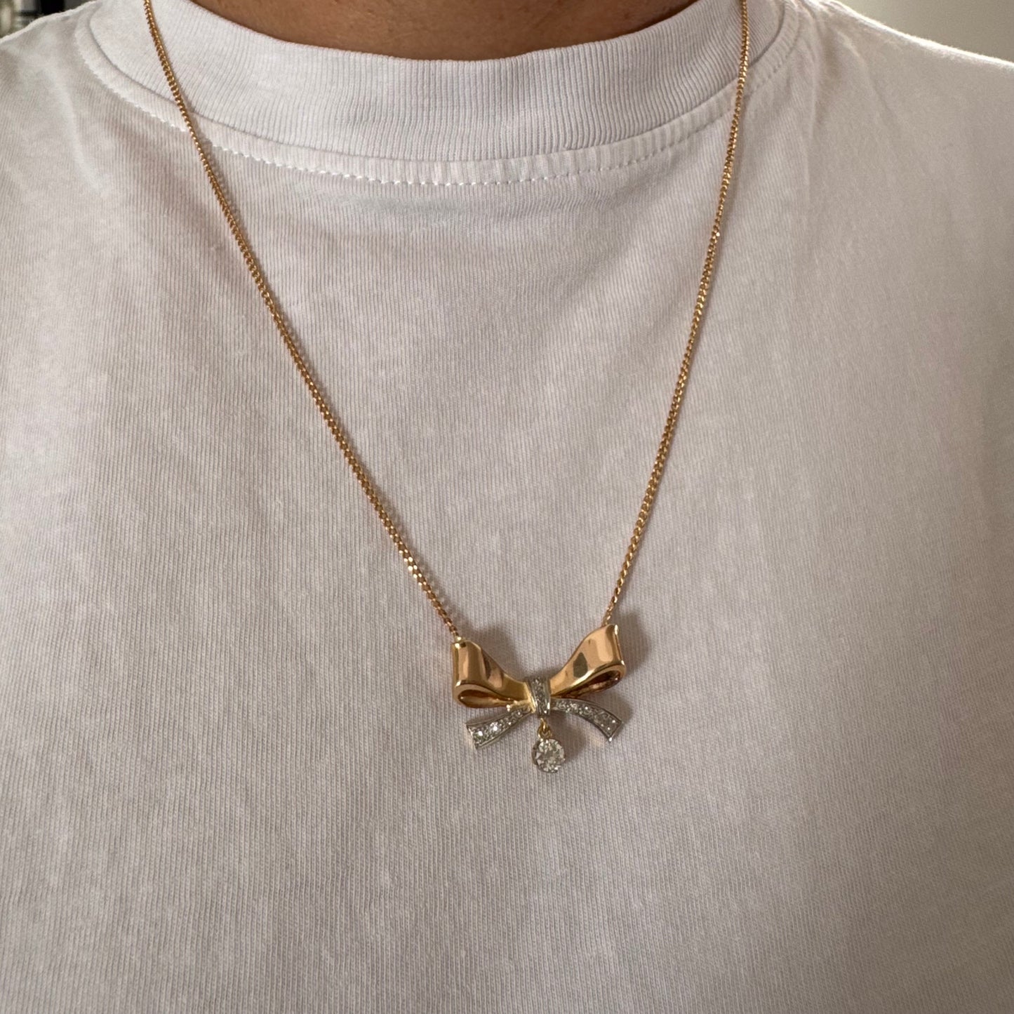 שרשרת זהב 18 קראט עם תליון בצורת סרט קלאסי משובץ יהלומים ונושא יהלום מרכזי תלוי שמוסיף נגיעה של זוהר ואלגנטיות