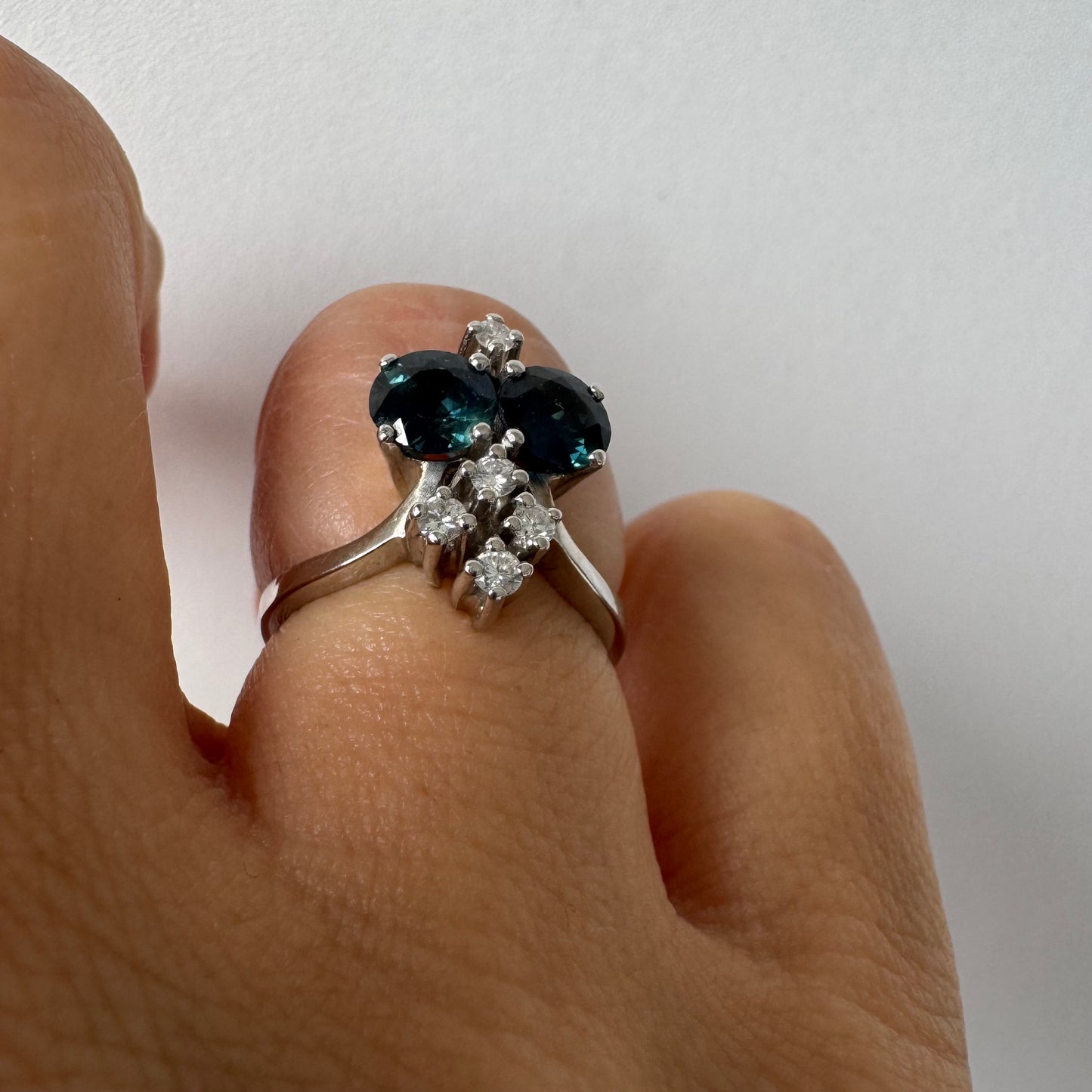 14K gold ring set with two deep blue oval Sapphires accented by clusters of brilliant white Diamonds.
