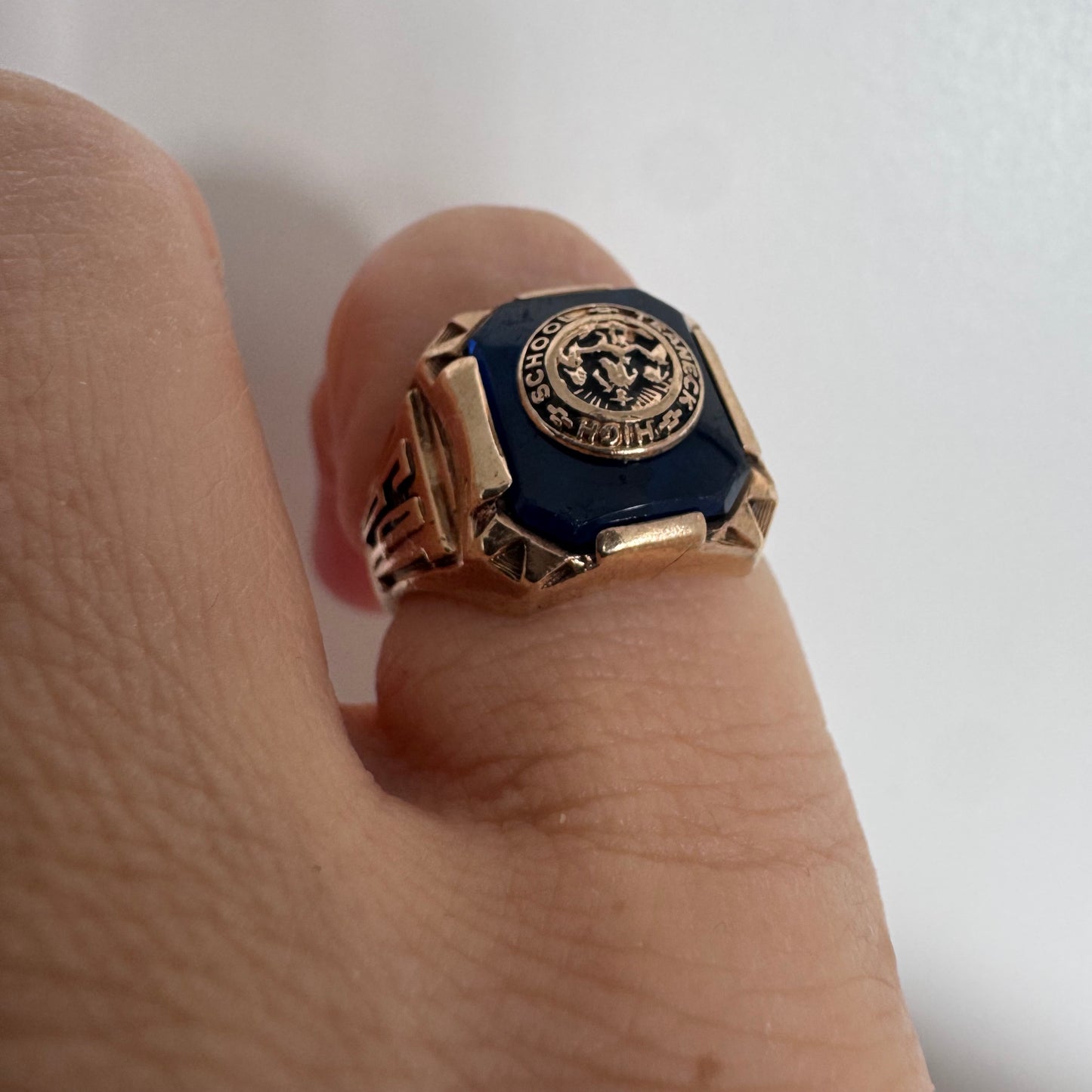 10K gold signet-style ring featuring a deep blue stone set with a raised “School & Teamwork” emblem at the center.
