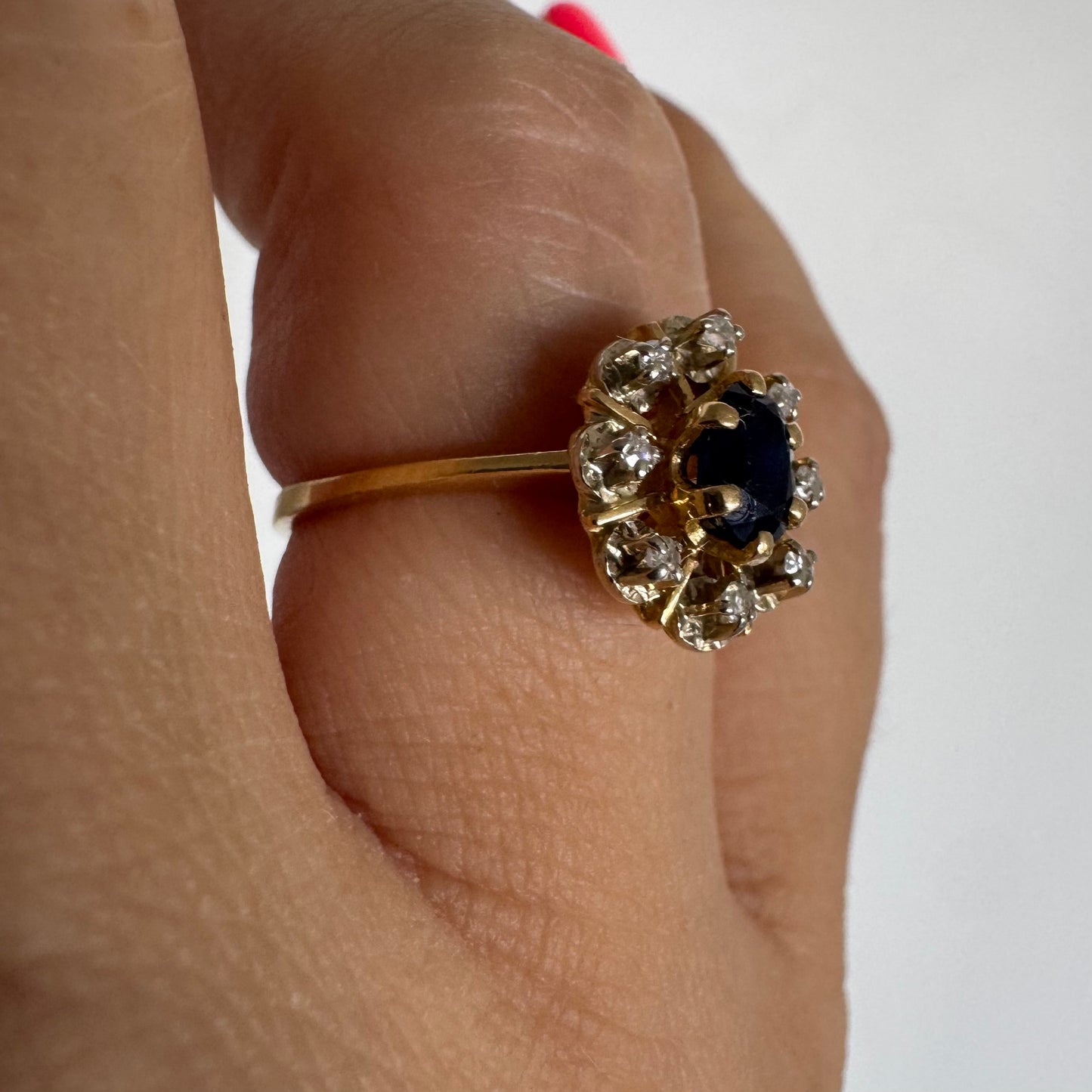 18K gold ring set with a natural blue Sapphire at its center, surrounded by a halo of sparkling Diamonds