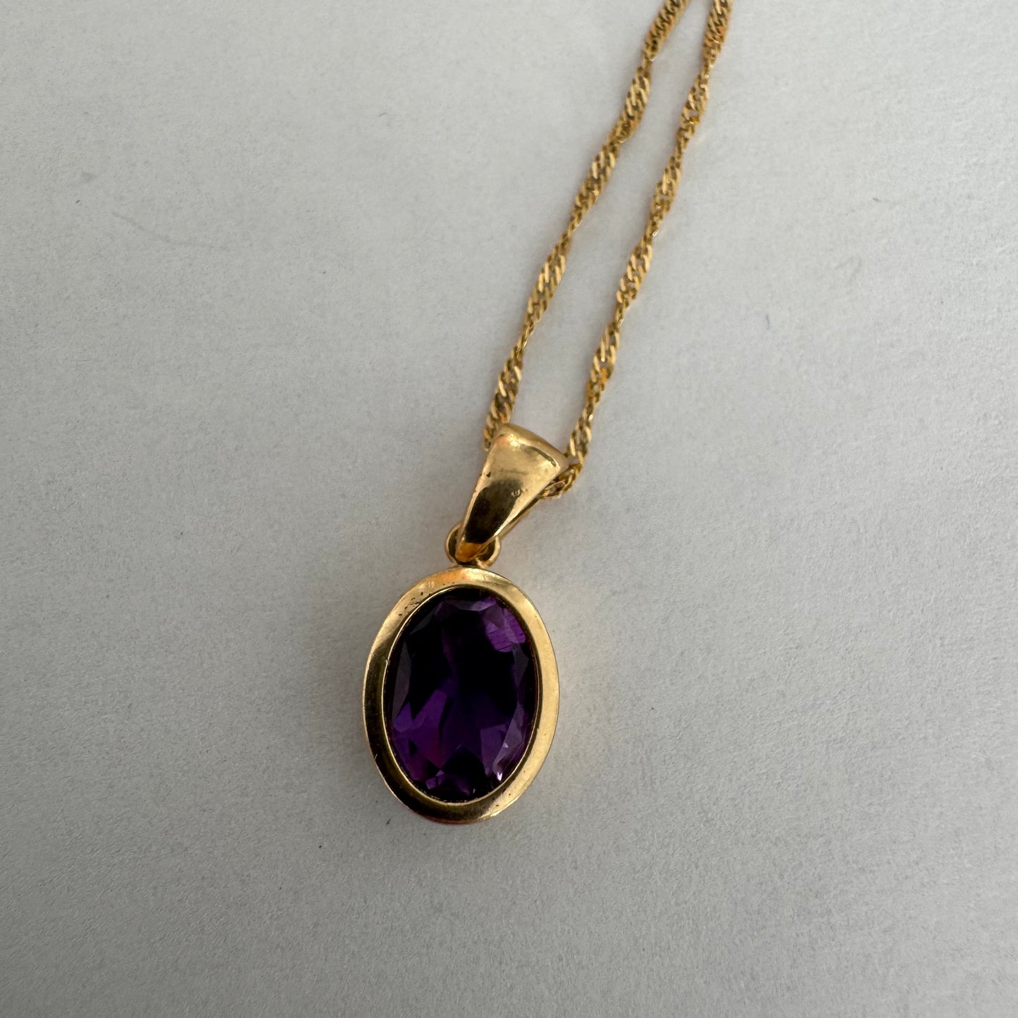 14K yellow gold necklace set with an oval-cut Amethyst in a smooth, classic bezel setting.