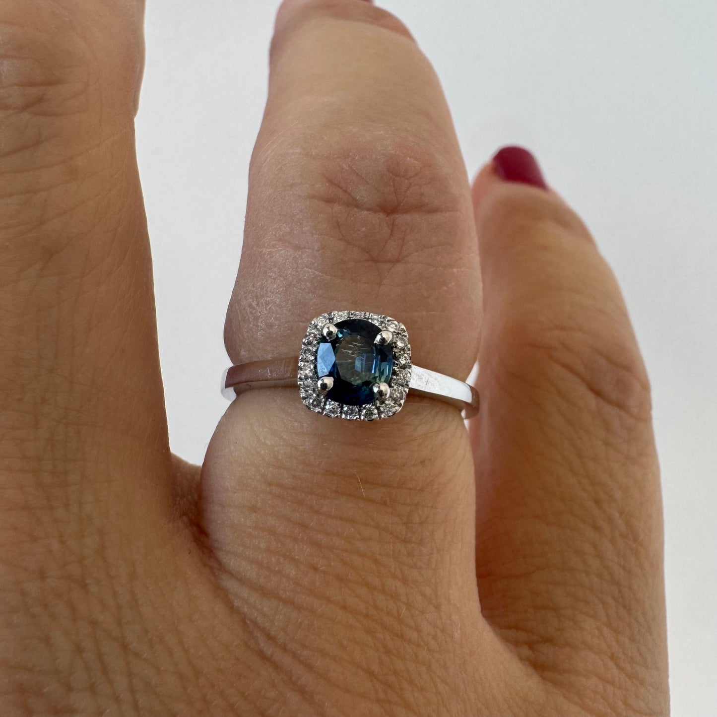 14K gold ring set with an oval blue Sapphire at the center framed by a delicate halo of sparkling Diamonds.