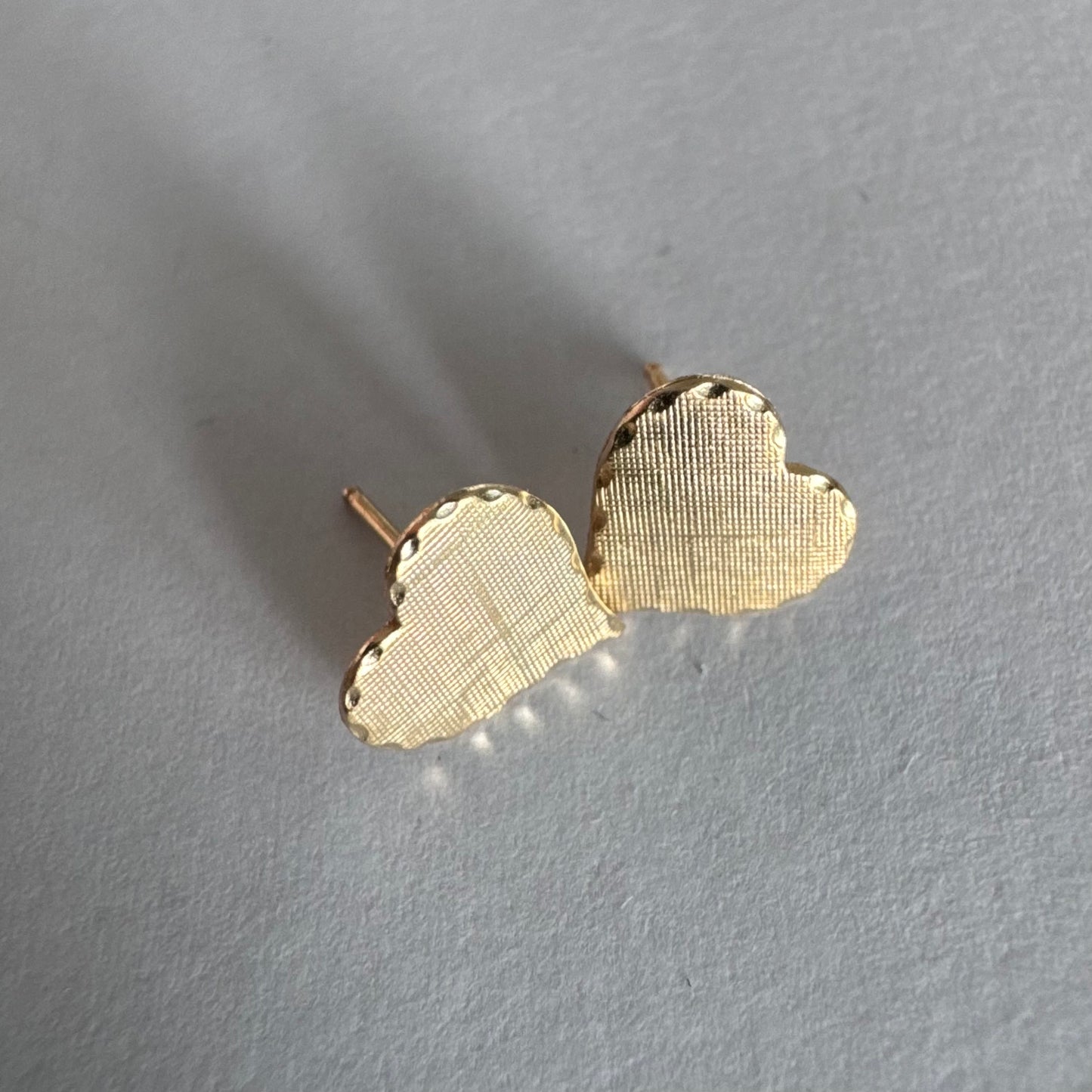 עגילי זהב צהוב 10 קראט בצורת לב, עם טקסטורה עדינה וגימור רך.