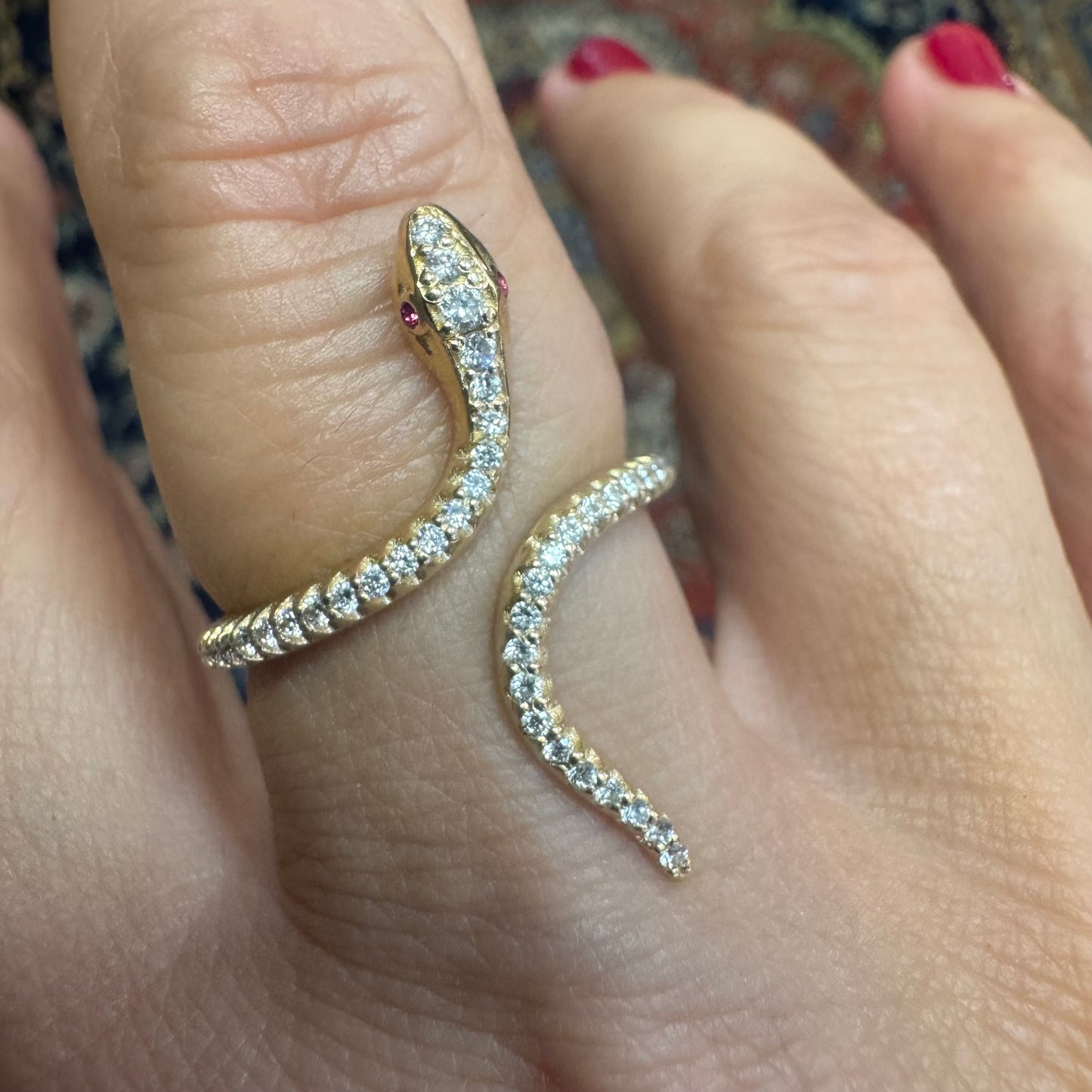 14K gold wrap-around snake ring, fully set with sparkling Diamonds along its body and head, finished with Rubies eyes