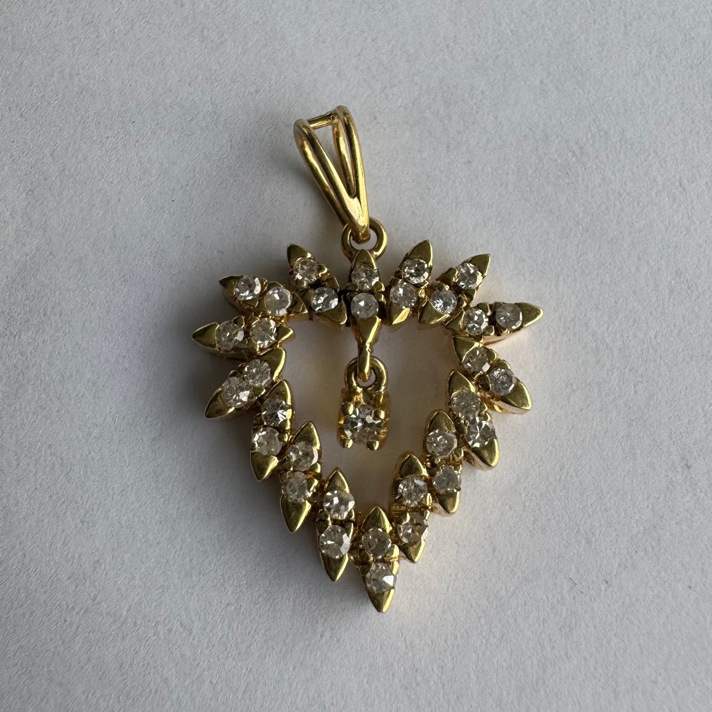 תליון זהב צהוב 14 קראט בצורת לב, משובץ יהלומים בסידור עדין היוצר מראה עשיר ומלא ברק.