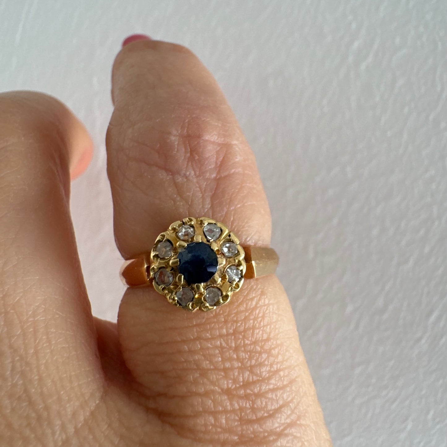 טבעת זהב 14 קראט משובצת ספיר מרכזי מוקף הילה של יהלומים בחיתוך עגול.