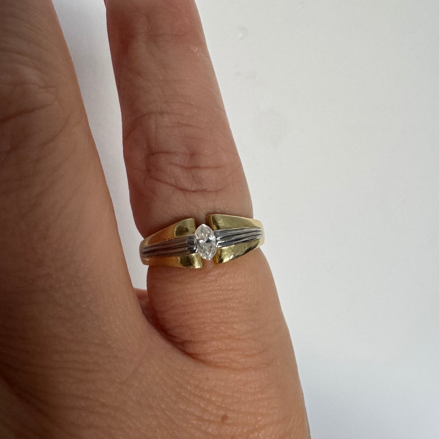 טבעת זהב 18 קראט בעיצוב דו-גוני של זהב צהוב ולבן, משובצת יהלום בחיתוך מרקיזה. 
