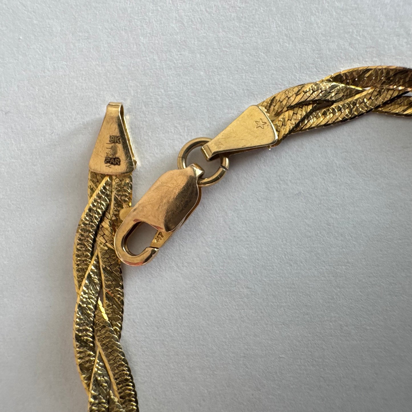 צמיד זהב צהוב 10 קראט בעיצוב קלוע עם טקסטורה עדינה שמחזירה אור וברק רך.