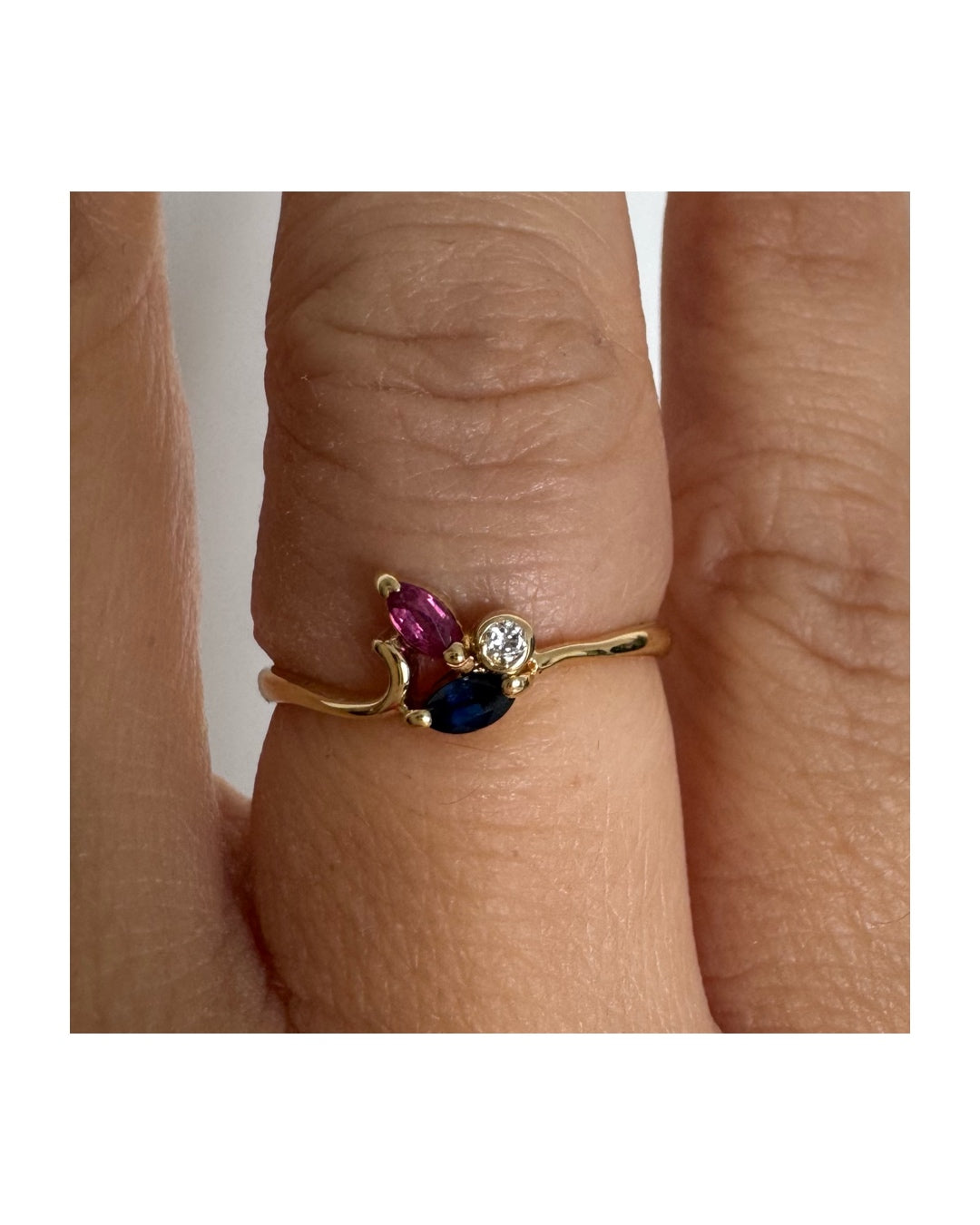 Delicate 18K gold ring set with pink and blue Sapphires alongside a sparkling center stone.