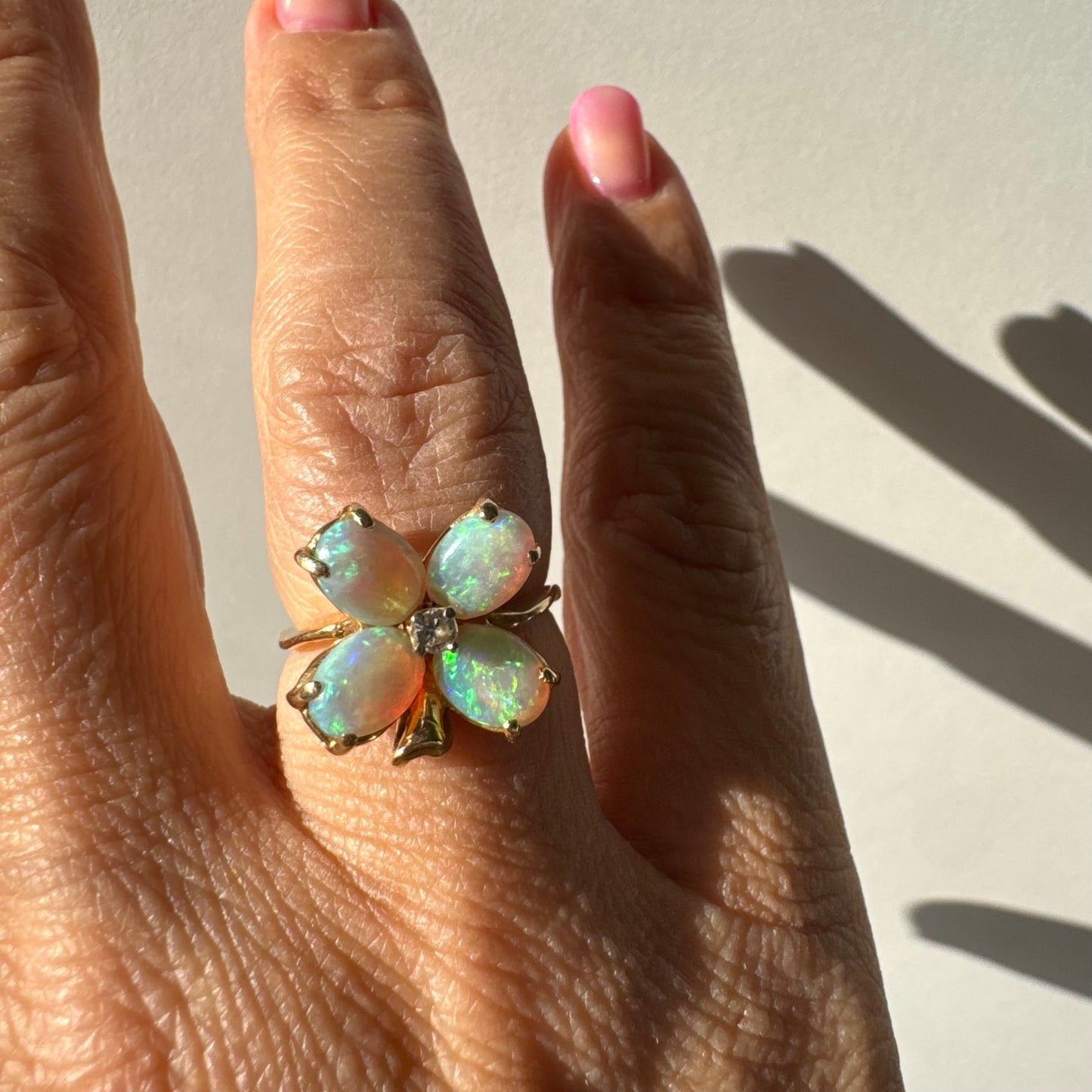 טבעת זהב 14 קראט בעיצוב פרח, משובצת ארבע אבני אופל בחיתוך טיפה ובמרכז יהלום טבעי.