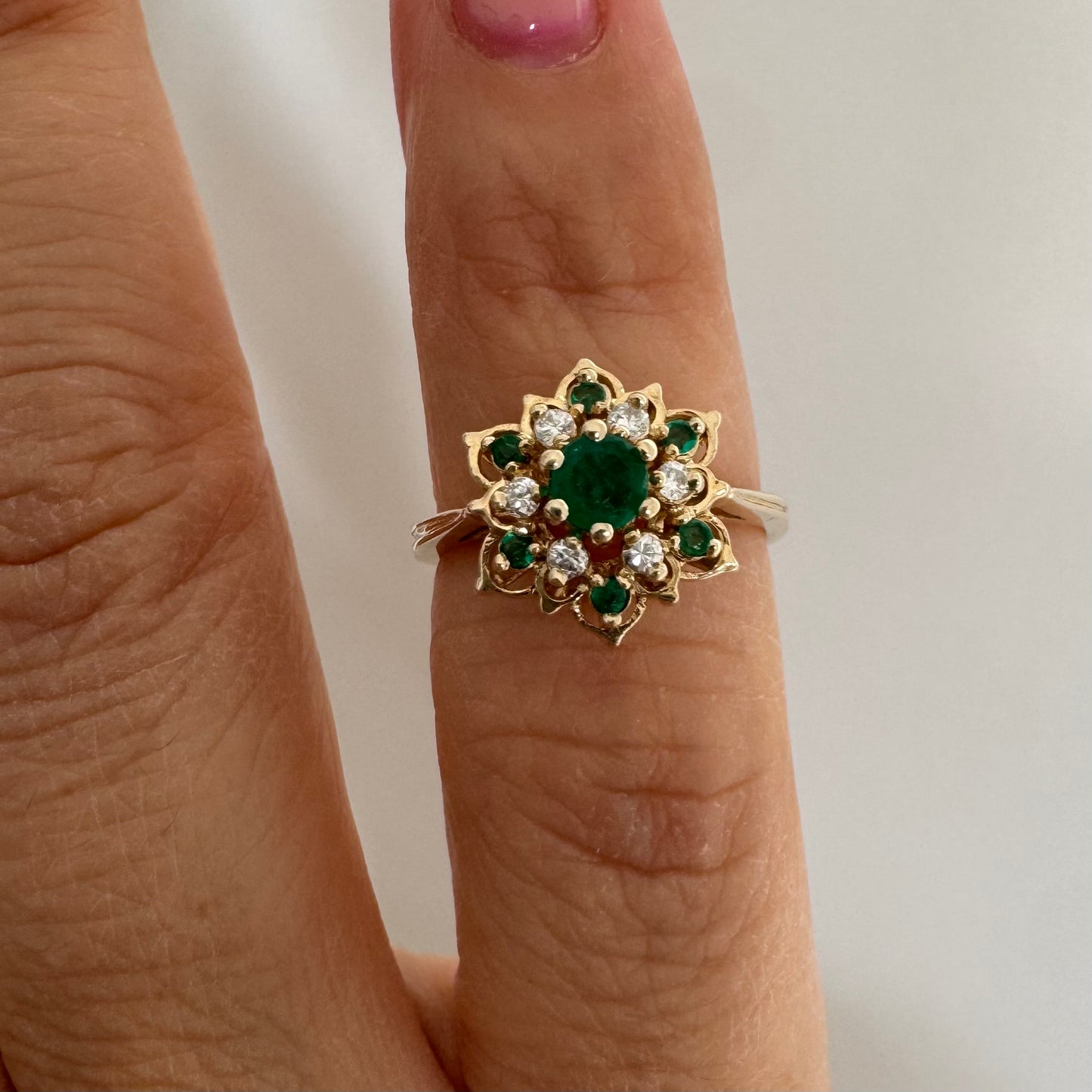 טבעת זהב 14 קראט בעיצוב פרח משובצת אבן אמרלד מרכזית, מוקפת יהלומים ואבני אמרלד נוספות