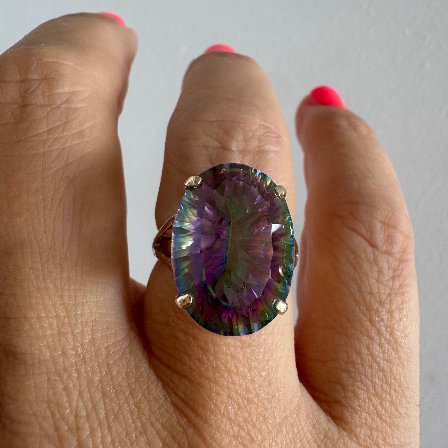 9K gold ring set with a large iridescent stone displaying mesmerizing shades of purple, green, and blue that shift beautifully in the light.