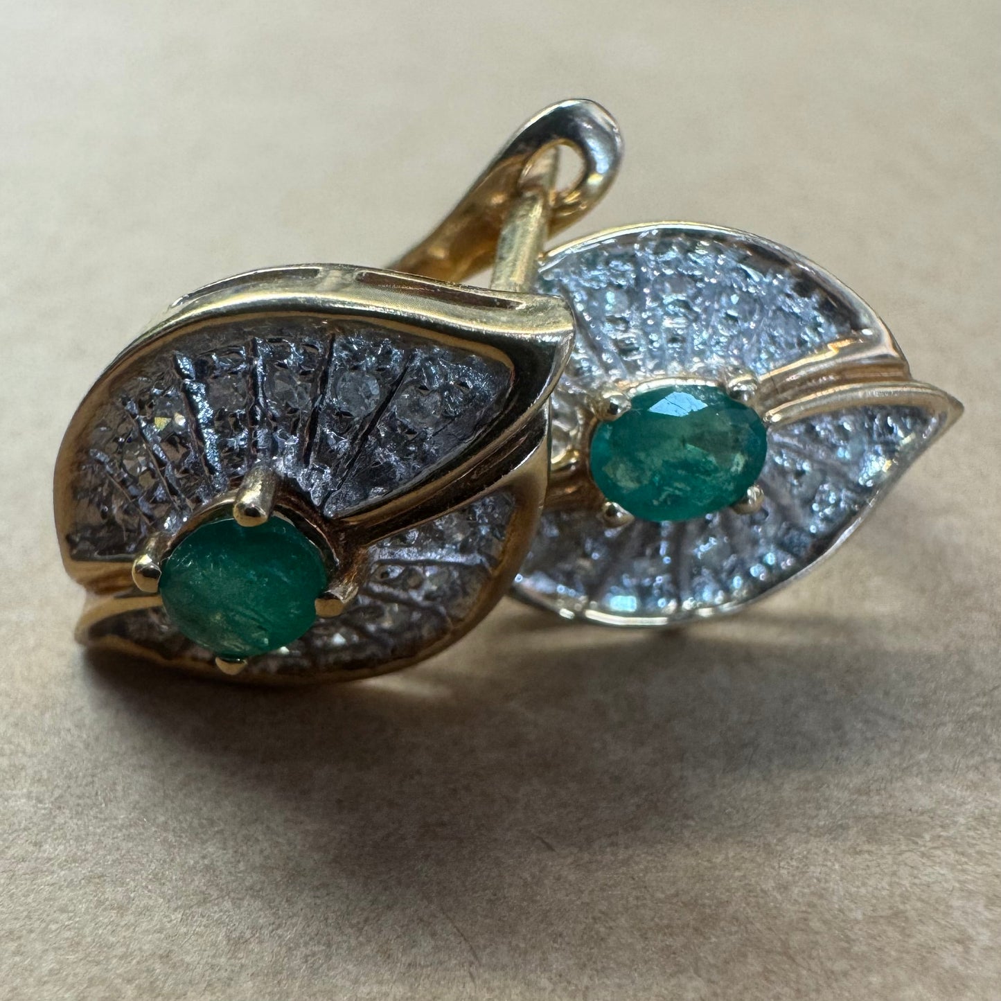 14K gold drop earrings in a refined leaf design, set with vivid green Emeralds at the center and shimmering pavé-set Diamonds along the curves