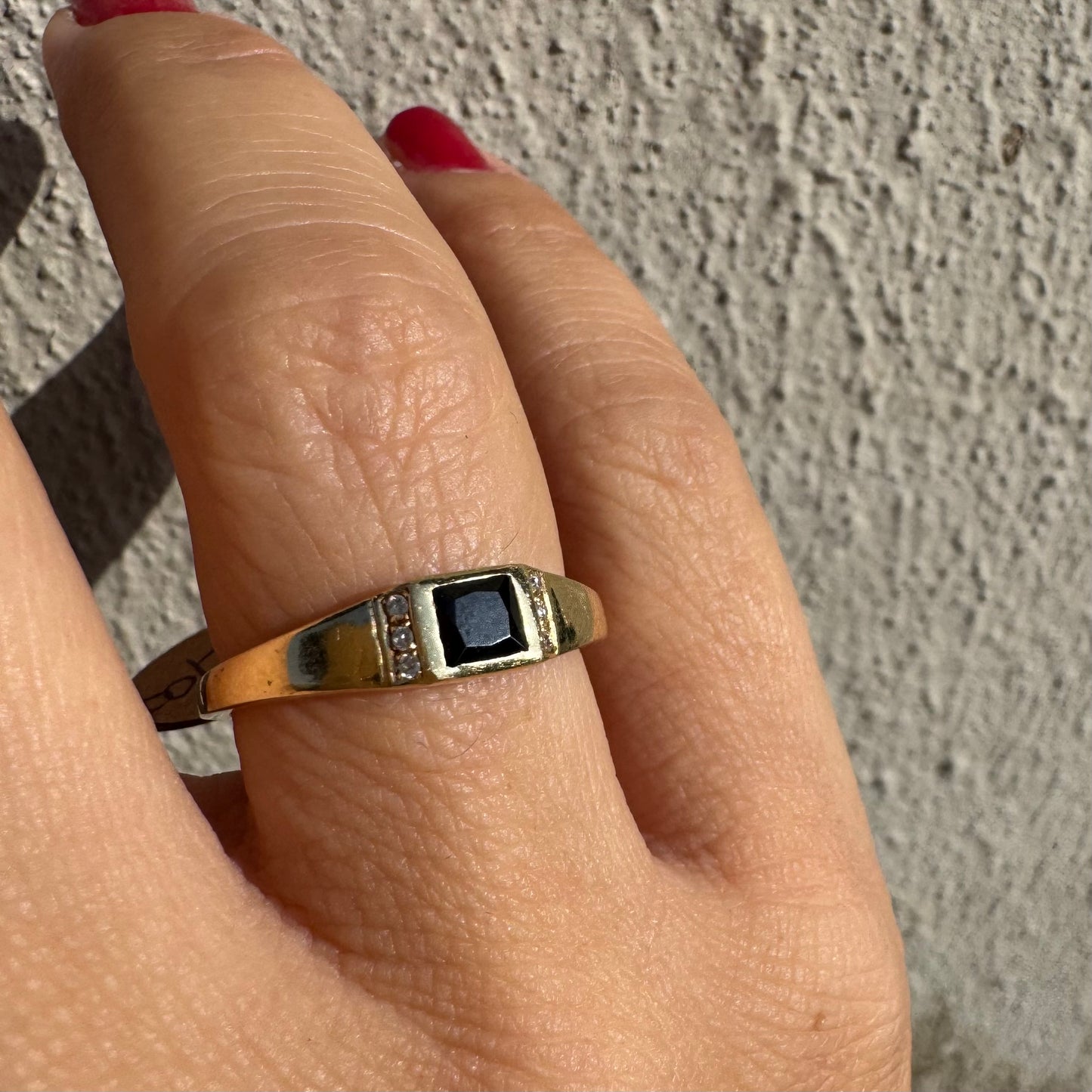 טבעת זהב 14 קראט משובצת אבן ספינל שחור בחיתוך ריבועי במרכז ויהלומים קטנים משני הצדדים.