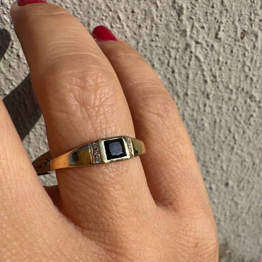 טבעת זהב 14 קראט משובצת אבן ספינל שחור בחיתוך ריבועי במרכז ויהלומים קטנים משני הצדדים.