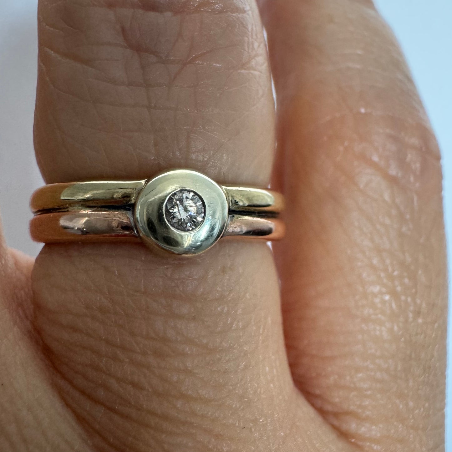 טבעת זהב 10 קראט בעיצוב מינימליסטי ונקי, משובצת יהלום מרכזי במסגרת חלקה (Bezel).