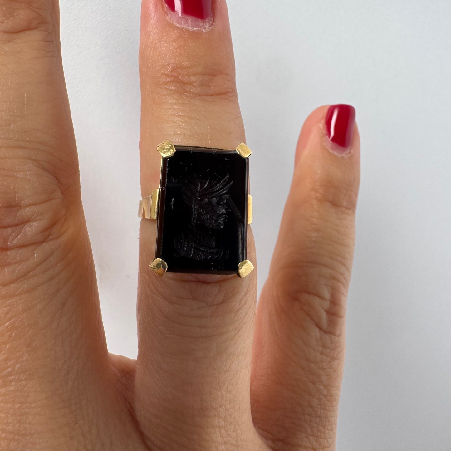 18K gold ring set with a carved dark stone featuring a classical warrior profile.