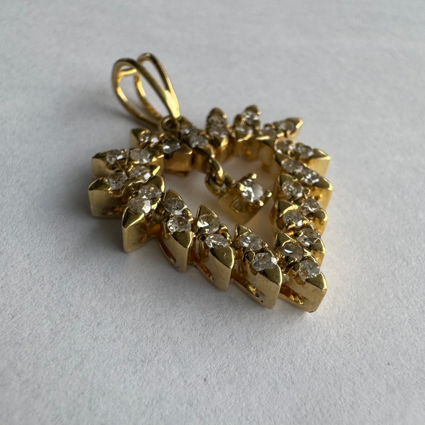 תליון זהב צהוב 14 קראט בצורת לב, משובץ יהלומים בסידור עדין היוצר מראה עשיר ומלא ברק.