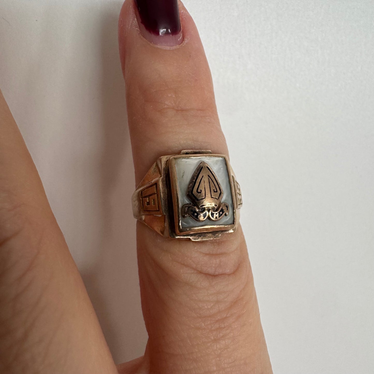 טבעת זהב 10 קראט בעיצוב חותם קלאסי, עם פלטה מרובעת משובצת לוח אם-הפנינה ועליה סמל פלר-דה-ליס מובלט.