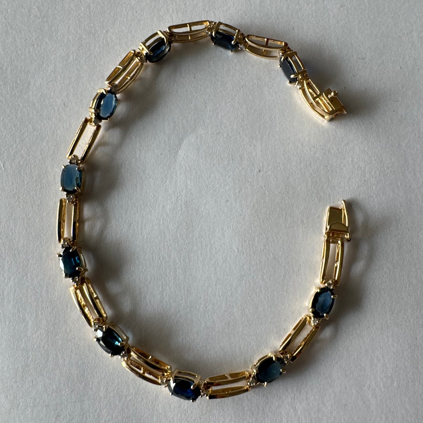 צמיד זהב צהוב 14 קראט משובץ אבני טופז כחולות בחיתוך אובלי, עם יהלומים המשובצים ביניהן להוספת ברק עדין.