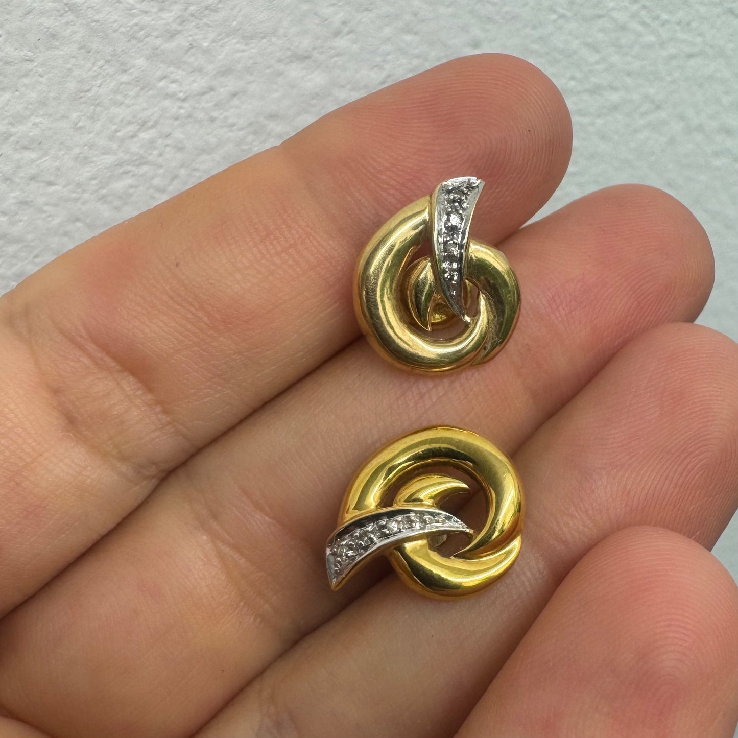 14K gold stud earrings set in a classic knot design, featuring a white gold accent adorned with sparkling Diamonds.