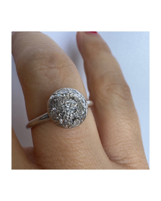 טבעת פלטינה עם אשכול עגול של יהלומים נוצצים במרכז, ליצירת מראה מודגש ואלגנטי