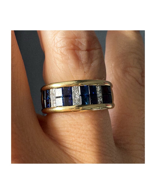 טבעת ה.שטרן זהב צהוב 18 קראט, בעיצוב רחב ומרשים. משובצת שורת אבני ספיר כחולות מרובעות בשילוב מחיצות של יהלומים לנגיעת ברק יוקרתי.