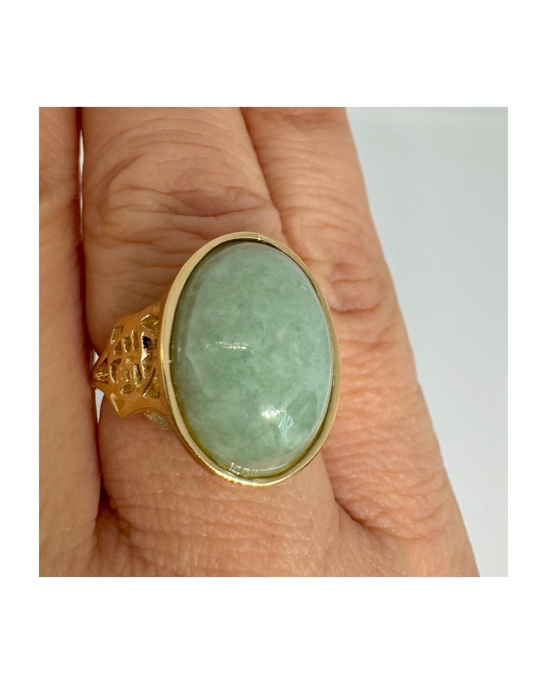 14K gold ring featuring a large oval light green Jade with a smooth polished finish, set in a classic bezel setting.