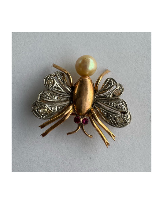 סיכת חרק ייחודית עשויה זהב 14 קראט משובצת יהלומים בעבודת פיליגרן עדינה בכנפיים, אבני רובי אדומות בעיניים ופנינה טבעית בגוון שמפניה.