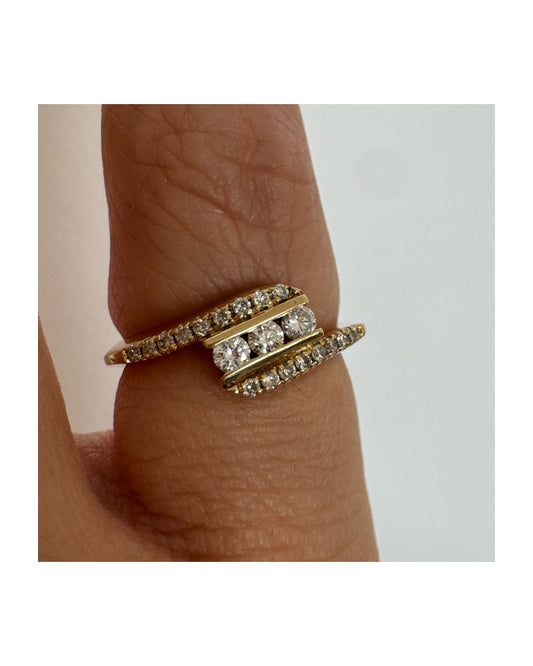 טבעת זהב צהוב 14 קראט בעיצוב ייחודי, משובצת שלושה יהלומים מרכזיים ושורות נוספות של יהלומים לאורך הזרועות. 