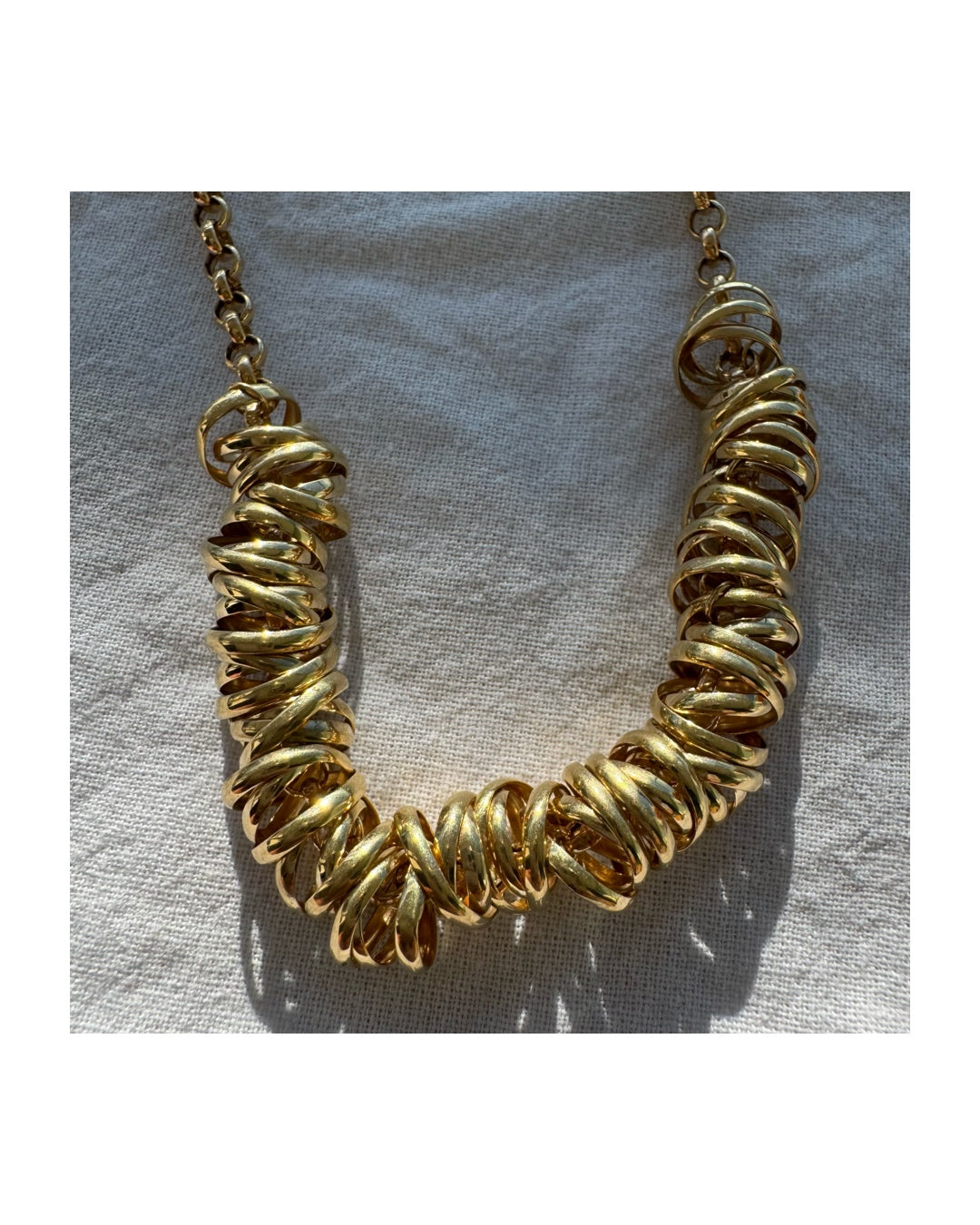 14K gold necklace featuring a series of intertwined gold rings creating a bold and sculptural design.